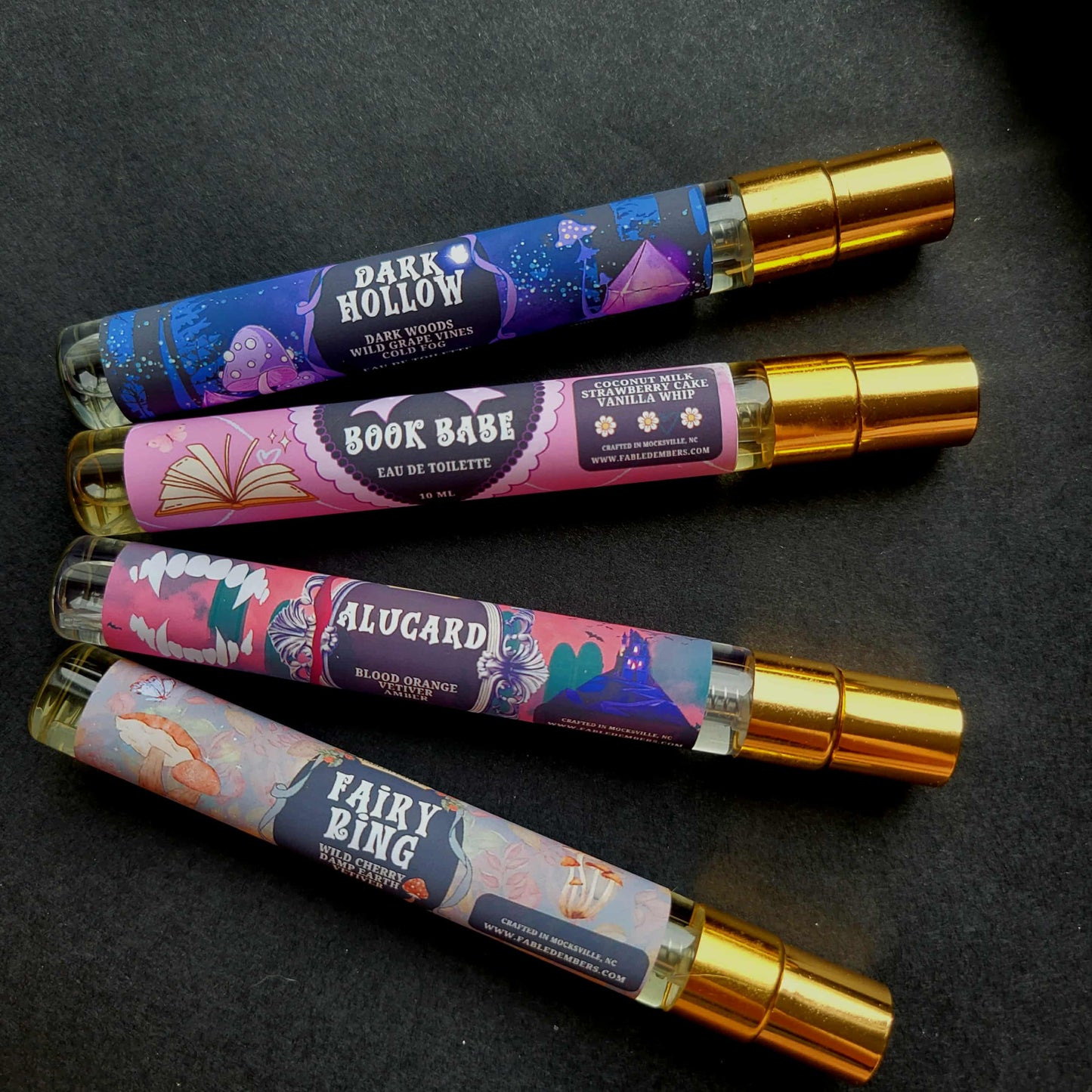 Five small perfume bottles with colorful labels on a dark background