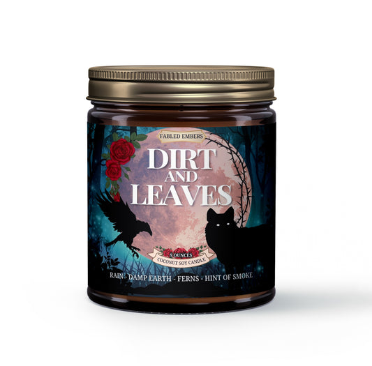 Amber jar "Dirt and Leaves" candle with a dark and moody label. Artwork depicts a black raven and a wolf in a shadowy forest scene with a full moon, red roses, and a touch of blue. Scent notes: rain, damp earth, ferns, and a hint of smoke. Bronze lid.