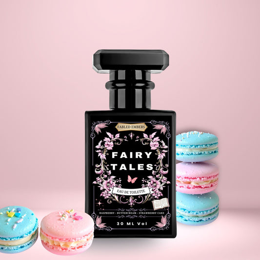 Fairy Tales EDT Perfume in a sleek matte black bottle with a pink floral high contrast label. Smells like Raspberry Strawberry Cake and Buttercream, on a soft pink background with blue and pink macarons.