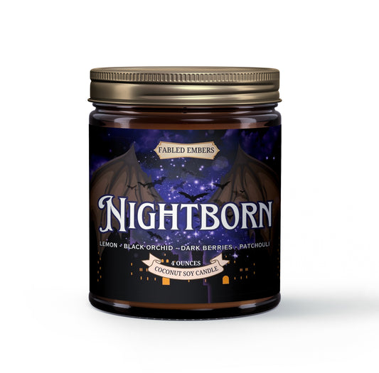 Amber jar candle with a dark label featuring prominent shadowy wings, a starry night sky with bats, and a gothic city silhouette. The candle is named "Nightborn" and has scent notes of Lemon, Black Orchid, Dark Berries, and Patchouli.