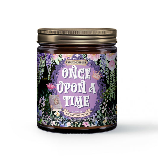 Amber jar candle with a purple label featuring an ornate frame, "Once Upon A Time" title, cascading pink and purple flowers, butterflies, and an open book. Scent notes include Blackberry Vines, Magnolia Petals, and Clover