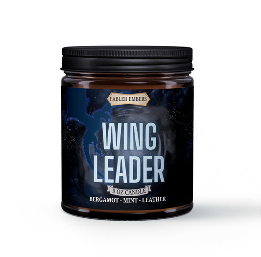 A jar candle labeled 'WING LEADER' with a dark label featuring a starry night and a silhouette of a dragon.