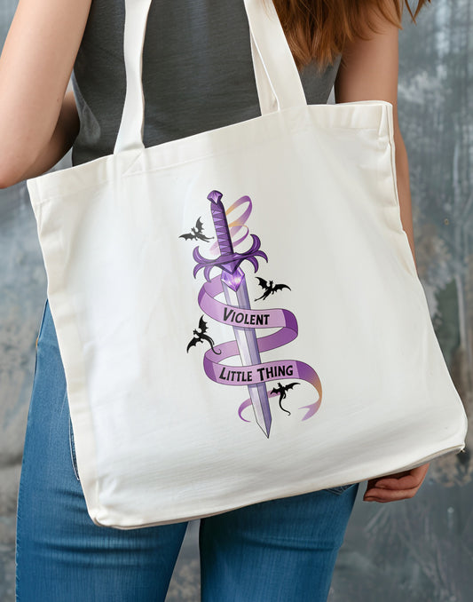 Person holding a tote bag with a purple ribbon design and text with a sword and dragons.