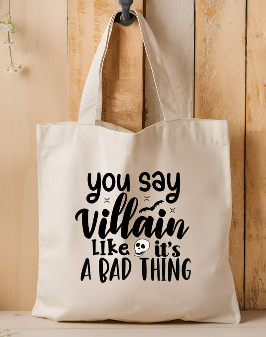 Tote bag with text 'you say villain like it's a bad thing' on a wooden background