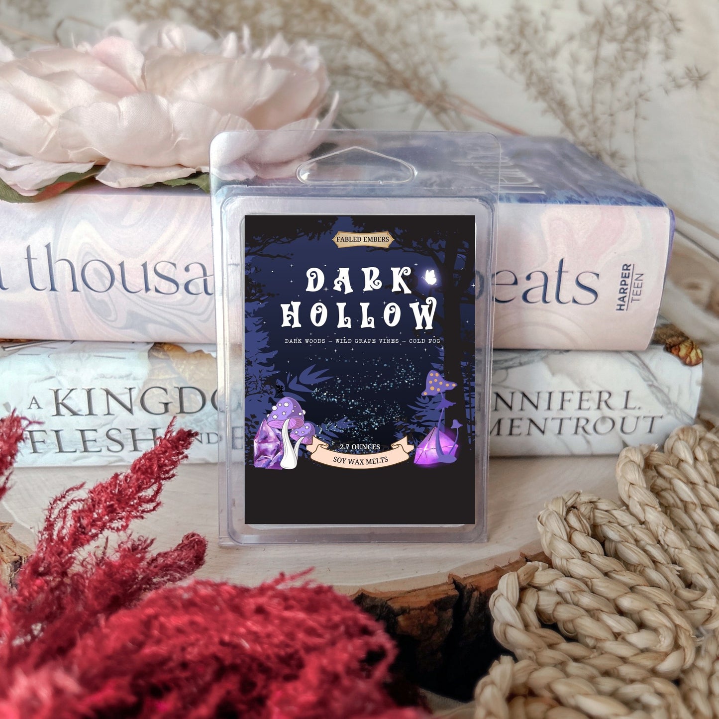 Box of 'Dark Hollow' candles on a surface with books and decorative items.