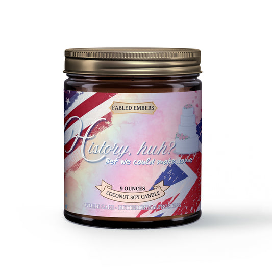 Amber jar candle with a distressed label featuring the US flag and Union Jack, a white tiered wedding cake, and the phrase "History, huh? Bet we could make some." The candle is scented with Wedding Cake, Buttercream, and Frosted Berries.