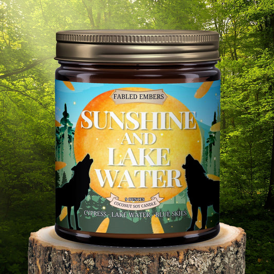 "Sunshine and Lake Water" coconut soy candle. Its vibrant label features howling wolves silhouetted against a setting sun, with a whimsical forest and bright blue skies. 