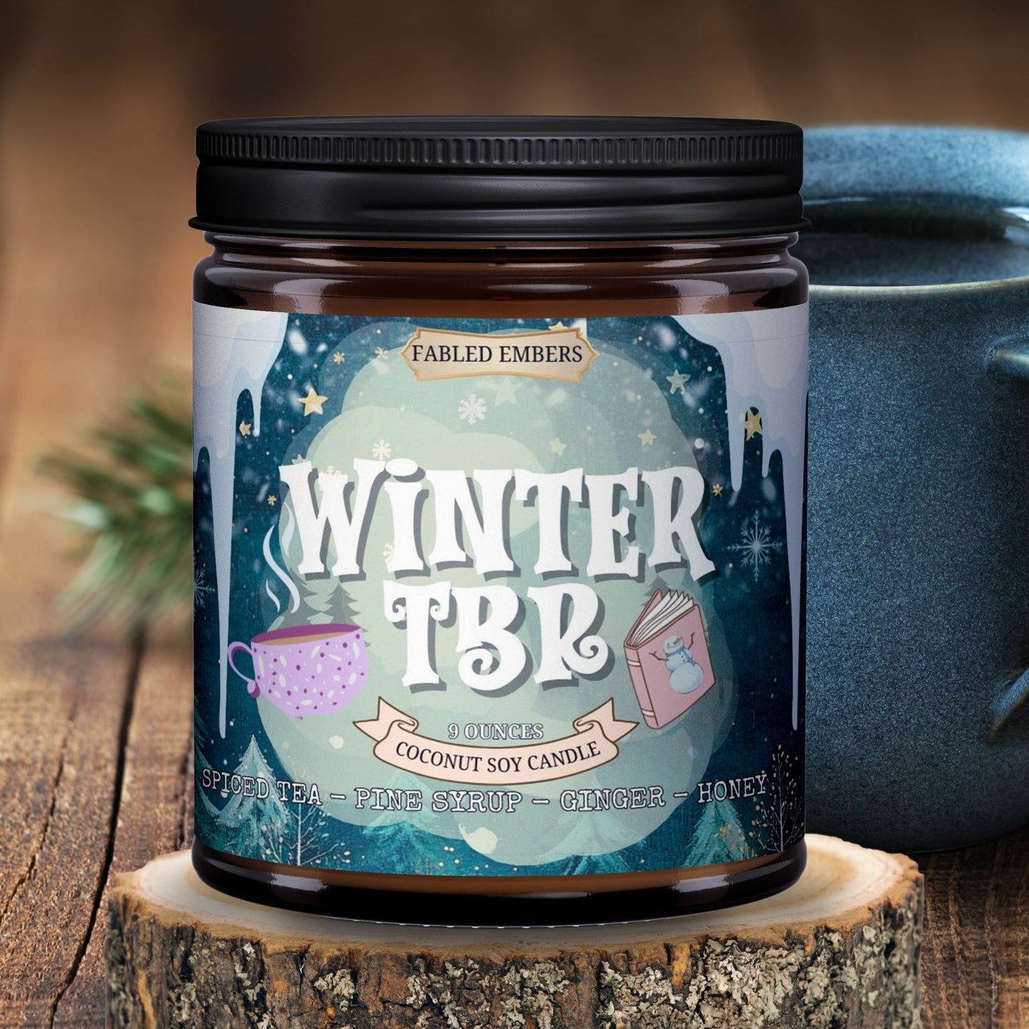 Candle jar labeled 'Winter TBR' by Fabled Embers on a wooden surface with a blurred background.